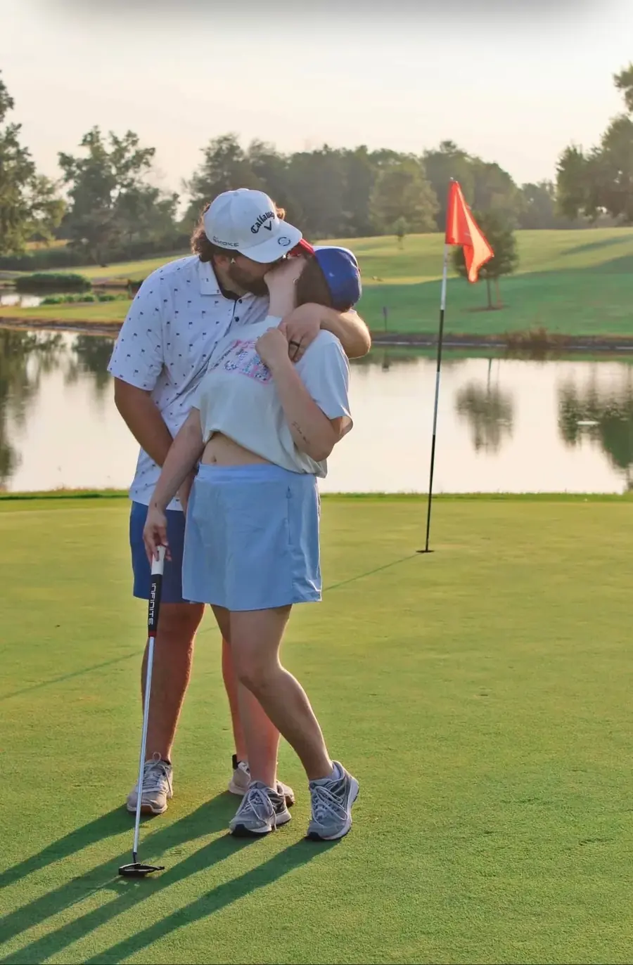 A couple embracing on the green at sunset